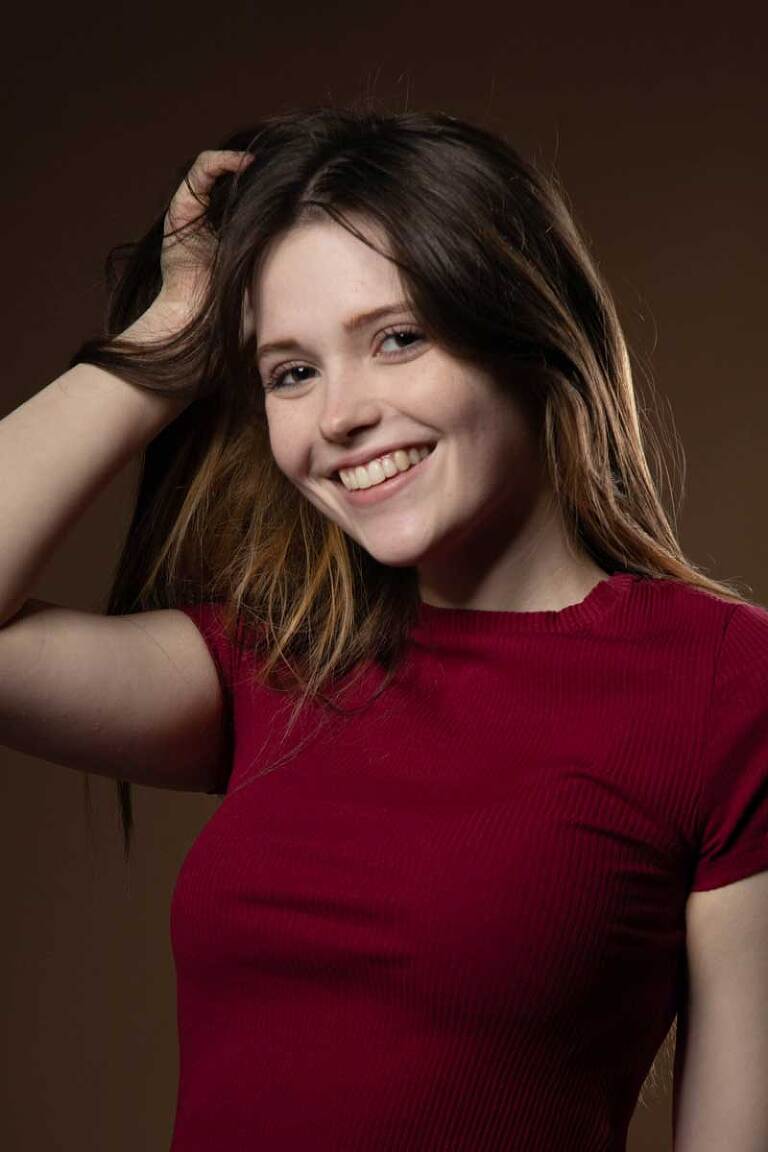 women's fashion headshot of smiling brunette woman wearing red in photography studio