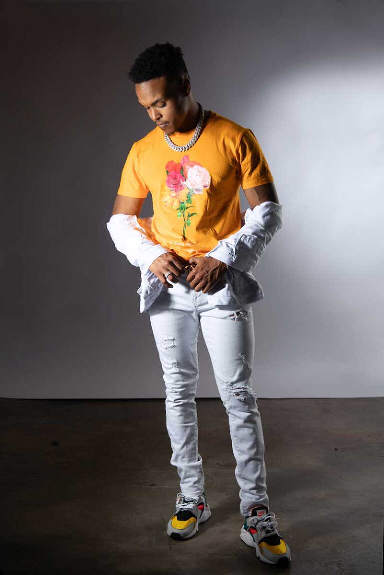 photograph of a male model full length showing off a white jacket for a fashion photoshoot