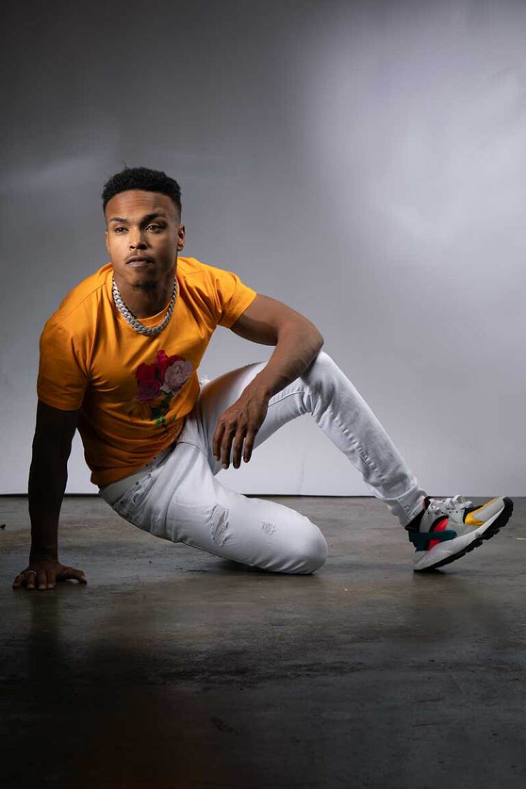 photograph of a male model posing on the ground in a full length fashion portrait